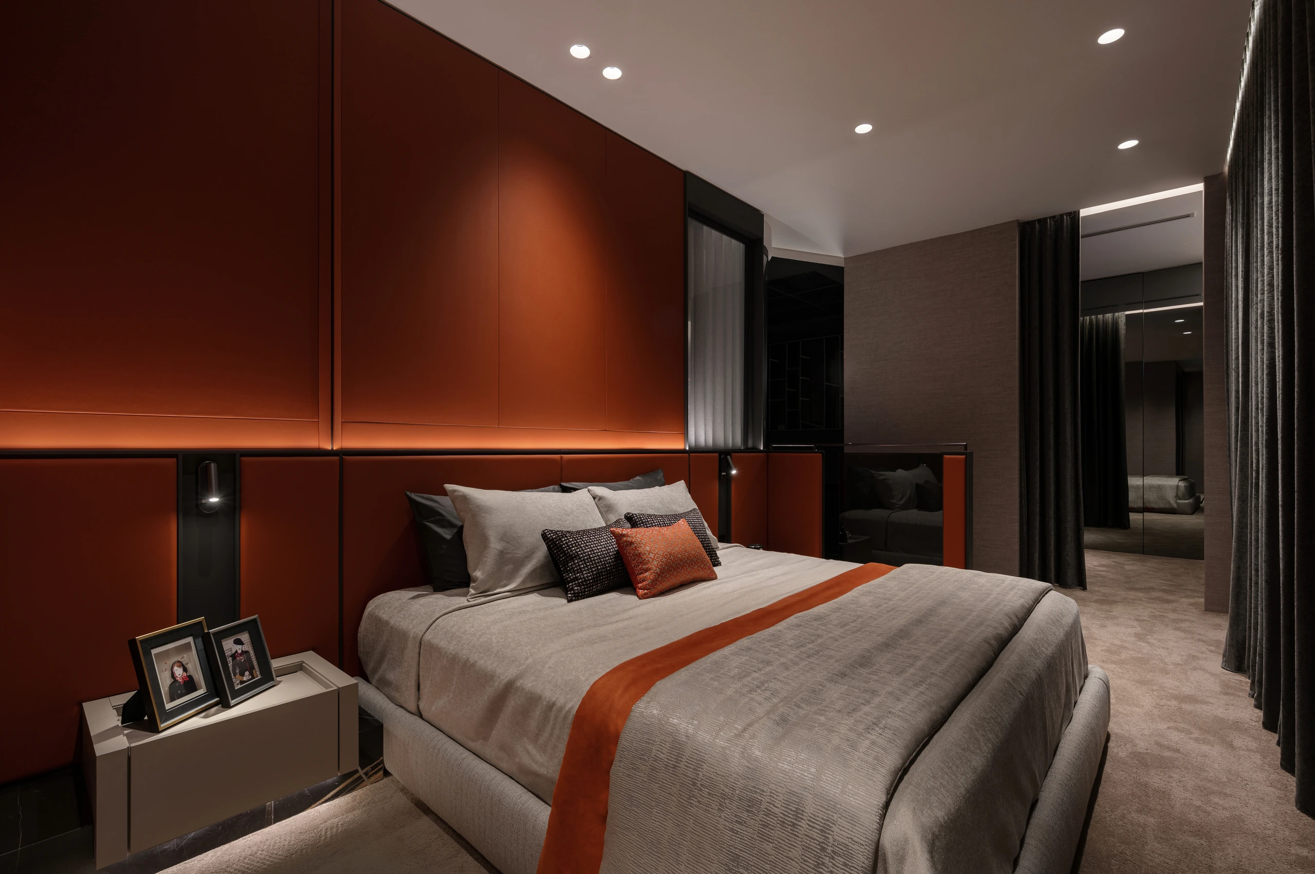 Burnt-orange master bedroom with integrated bedside lighting by Edgeline Planners