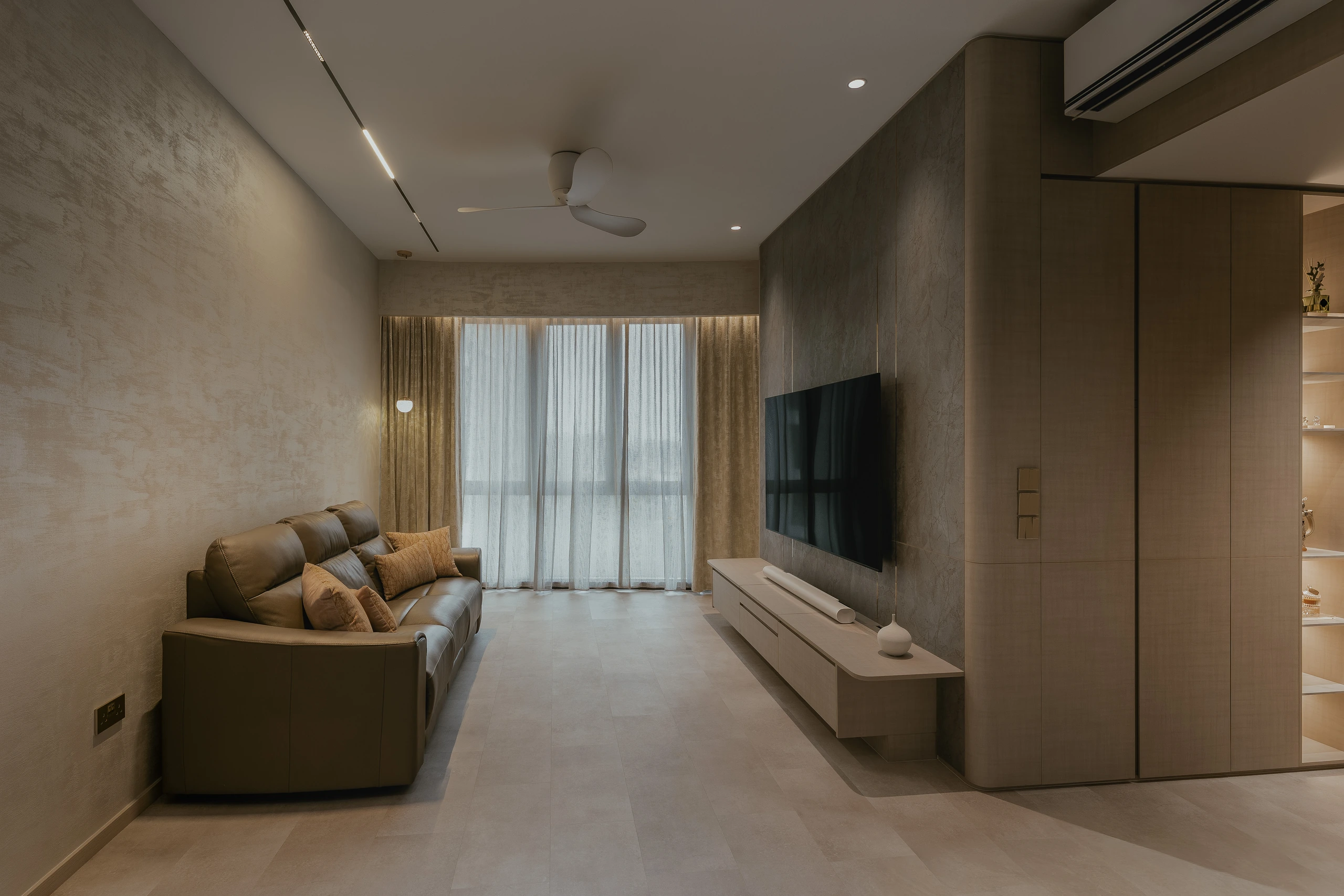 Living room with textured wall and pale media console by Edgeline Planners