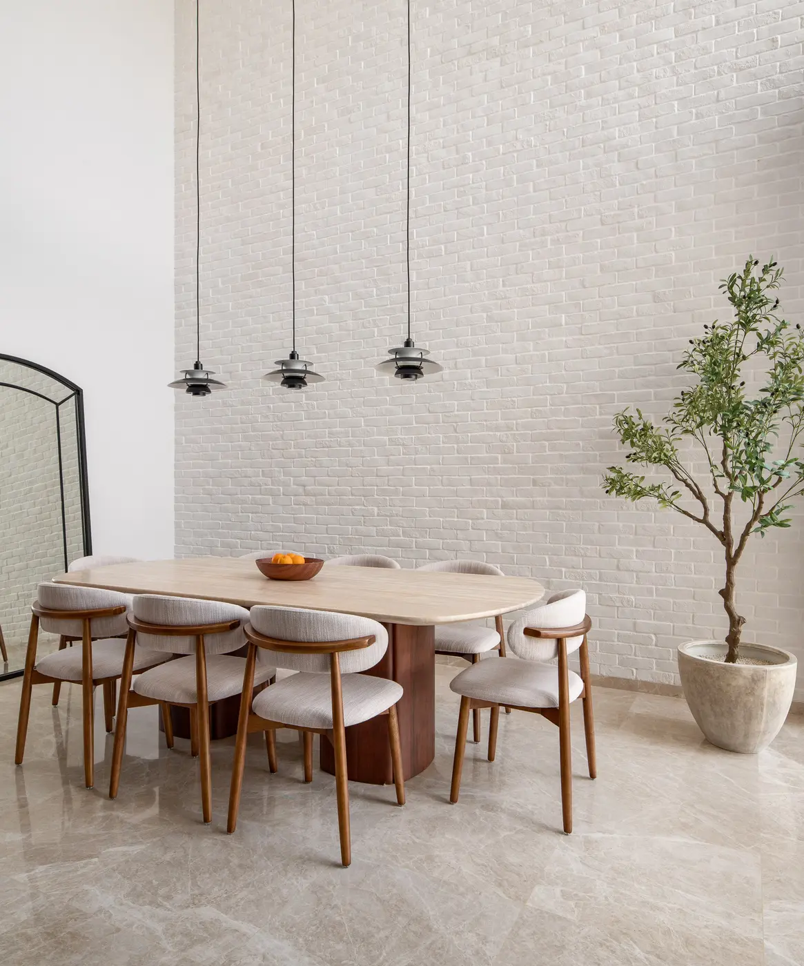 Double-volume dining area with aged white brick wall and olive tree