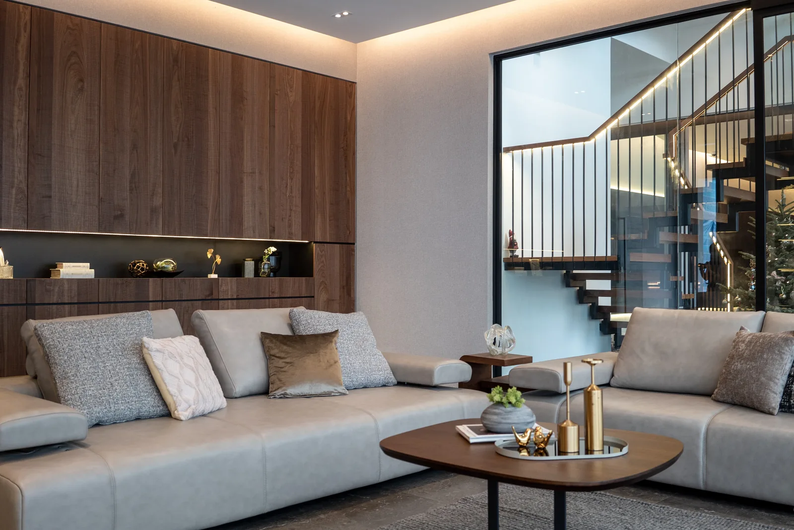 J Concept Designers &mdash; living room sofa wall with display niche and open staircase beyond glass