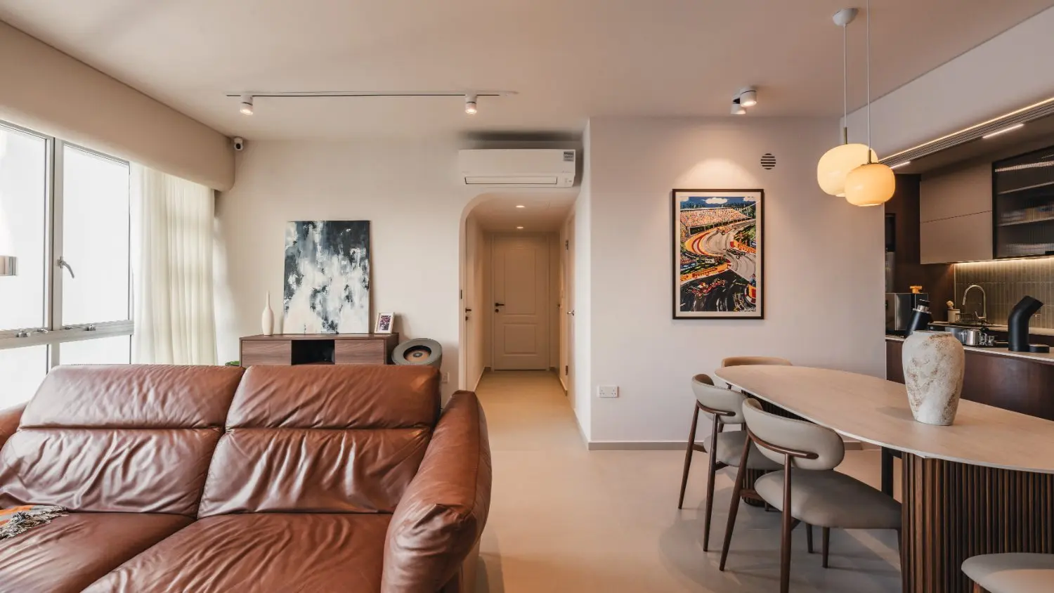 Living room with leather sofa beside the dining area and private hallway