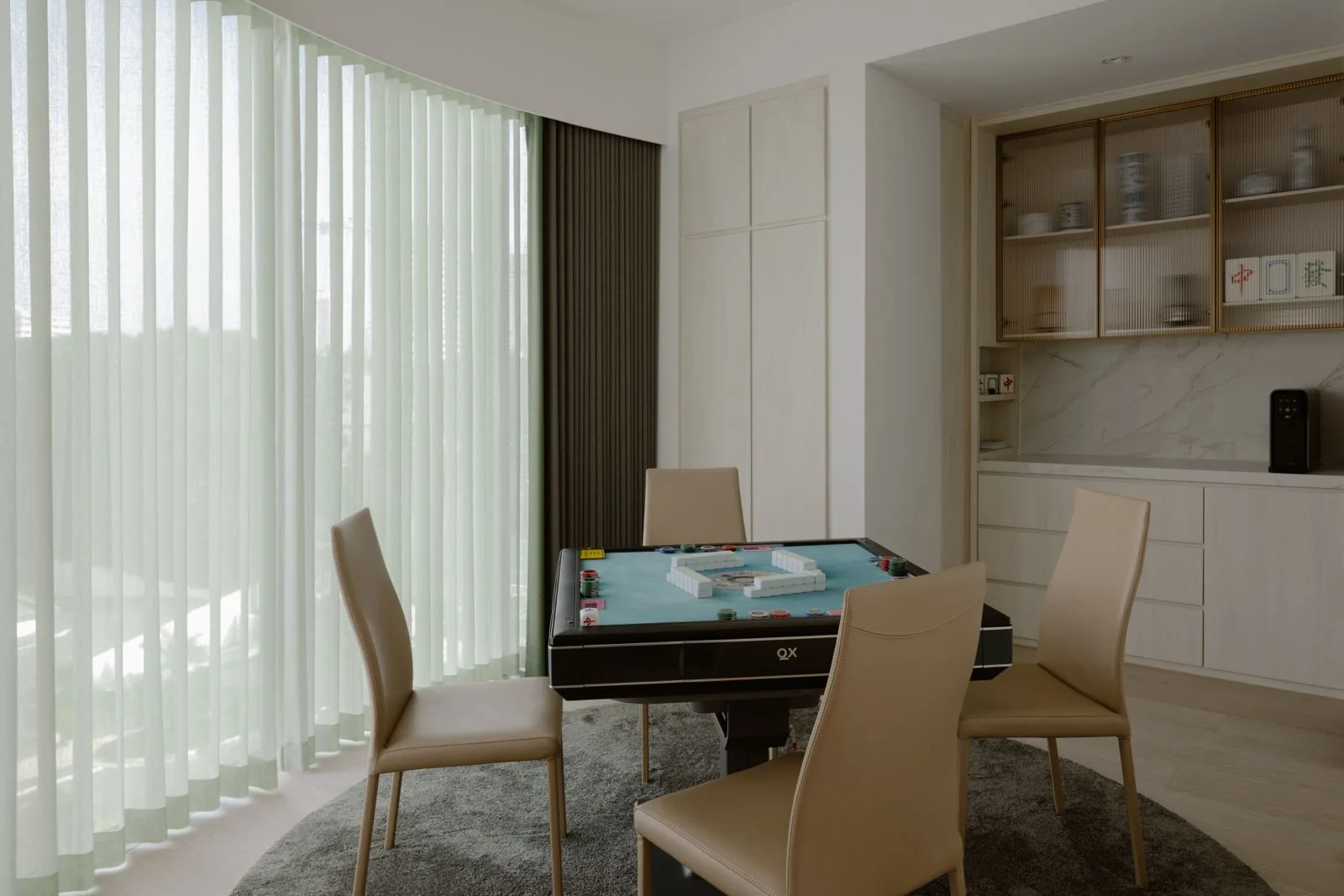Mahjong table set beside a softly curtained window and display cabinetry