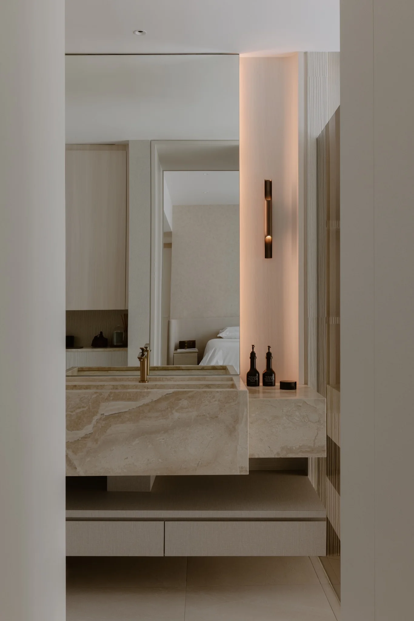 Stone sink and mirror beside the master bedroom, with the bed visible beyond